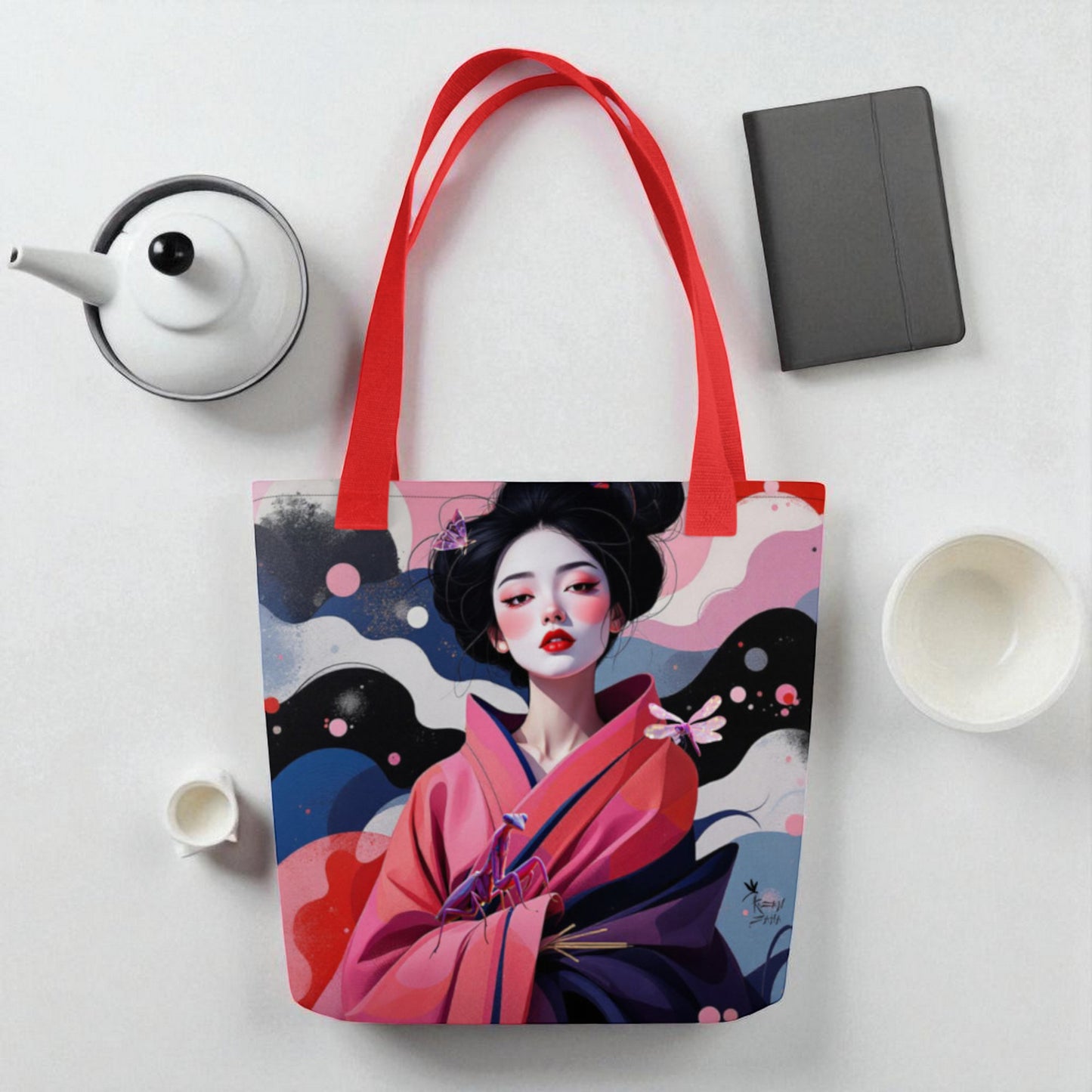 Bolso tote Geisha Rosa sobre superficie blanca en composición de estudio con tazas de té y cuaderno, asas .ojas