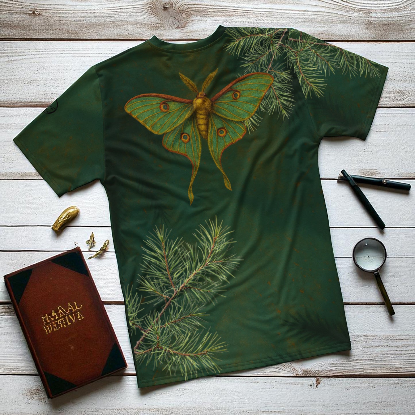camiseta polilla verde sobre una mesa diseño posterior con mariposa nocturna entre ramas de pino