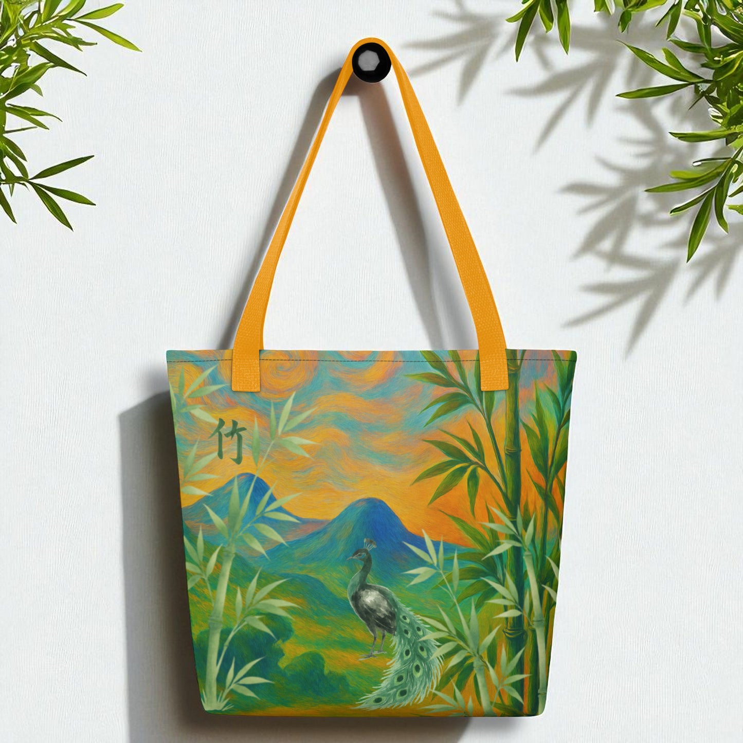 Bolso tote bambú y pavo real, frontal, colgado,asas amrillas, fondo blanco con hojas de bambú