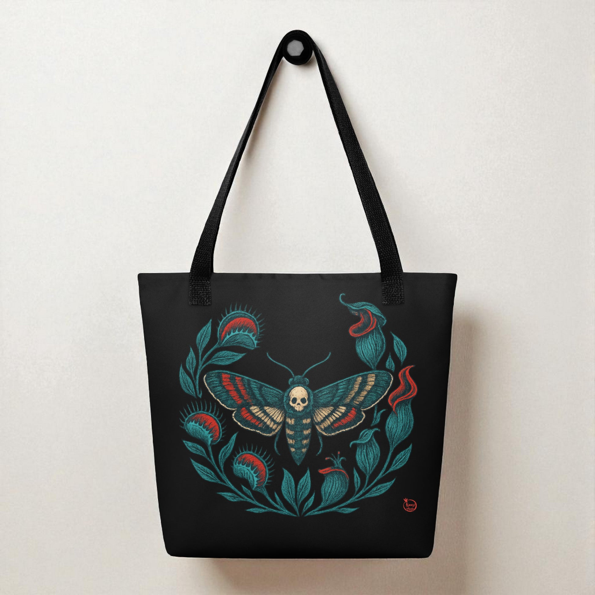 Bolso tote negro con polilla calavera colgado, primer plano del estampado y asas.