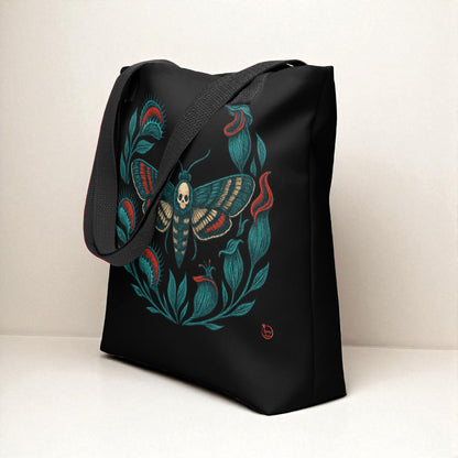 Vista lateral del bolso tote negro con polilla calavera, asas negras.