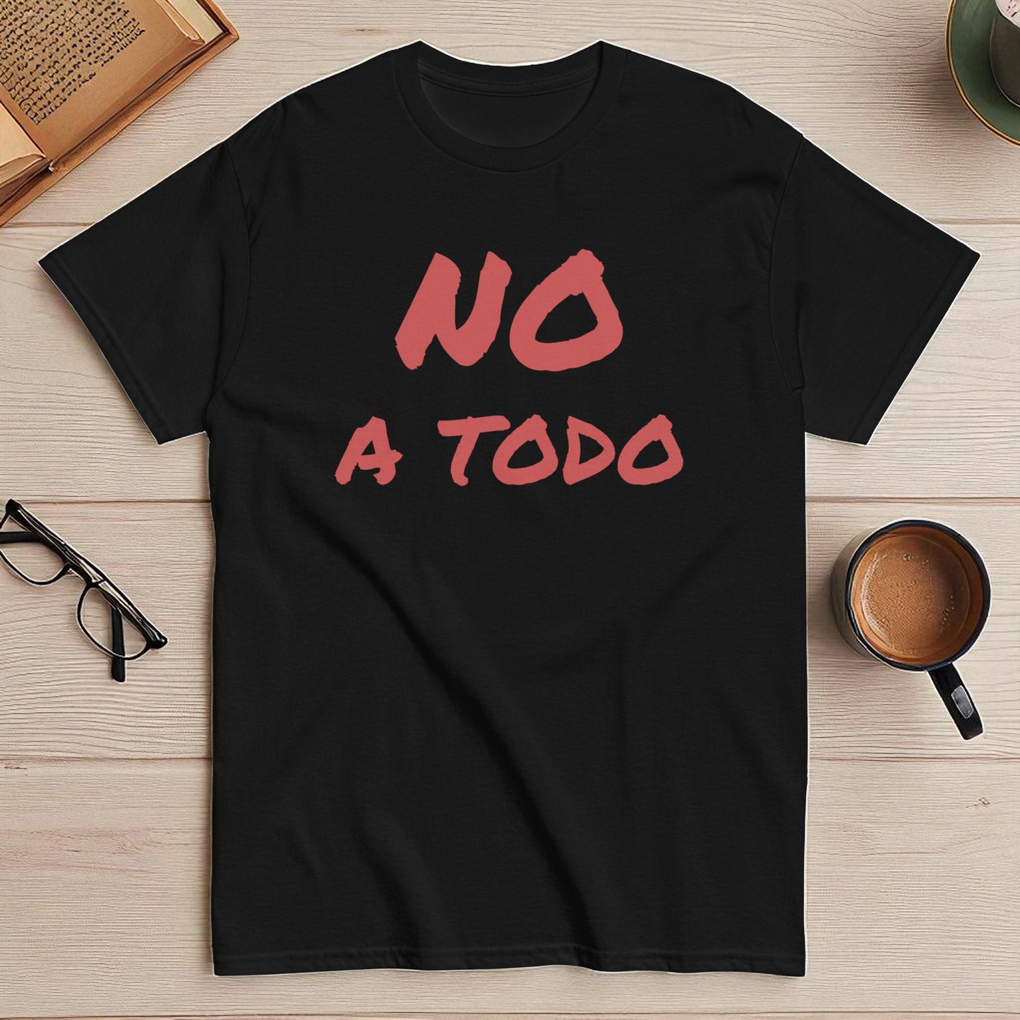 Camiseta negra con la frase no a todo diseño frontal en composicion flatlay con accesorios de escritorio