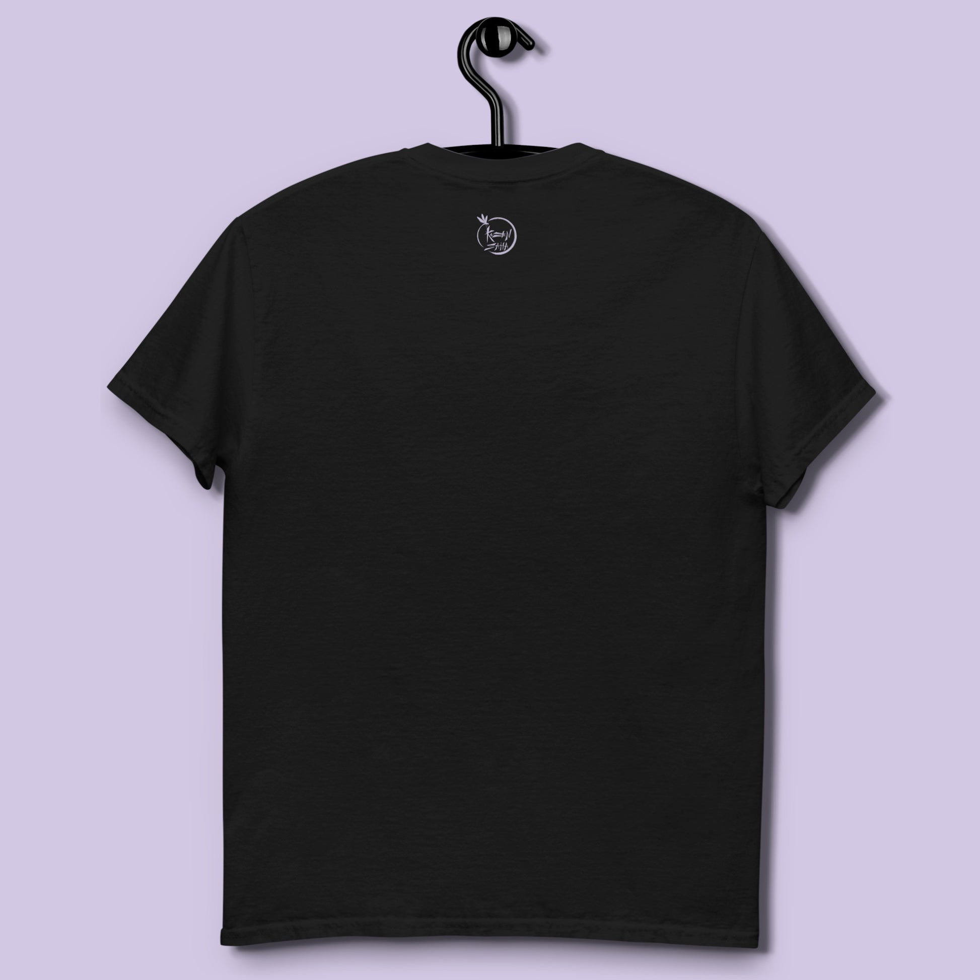 Camiseta negra unisex con frase Si callo me salen subtítulos colgada en percha vista espalda con logo Kuzen Saha