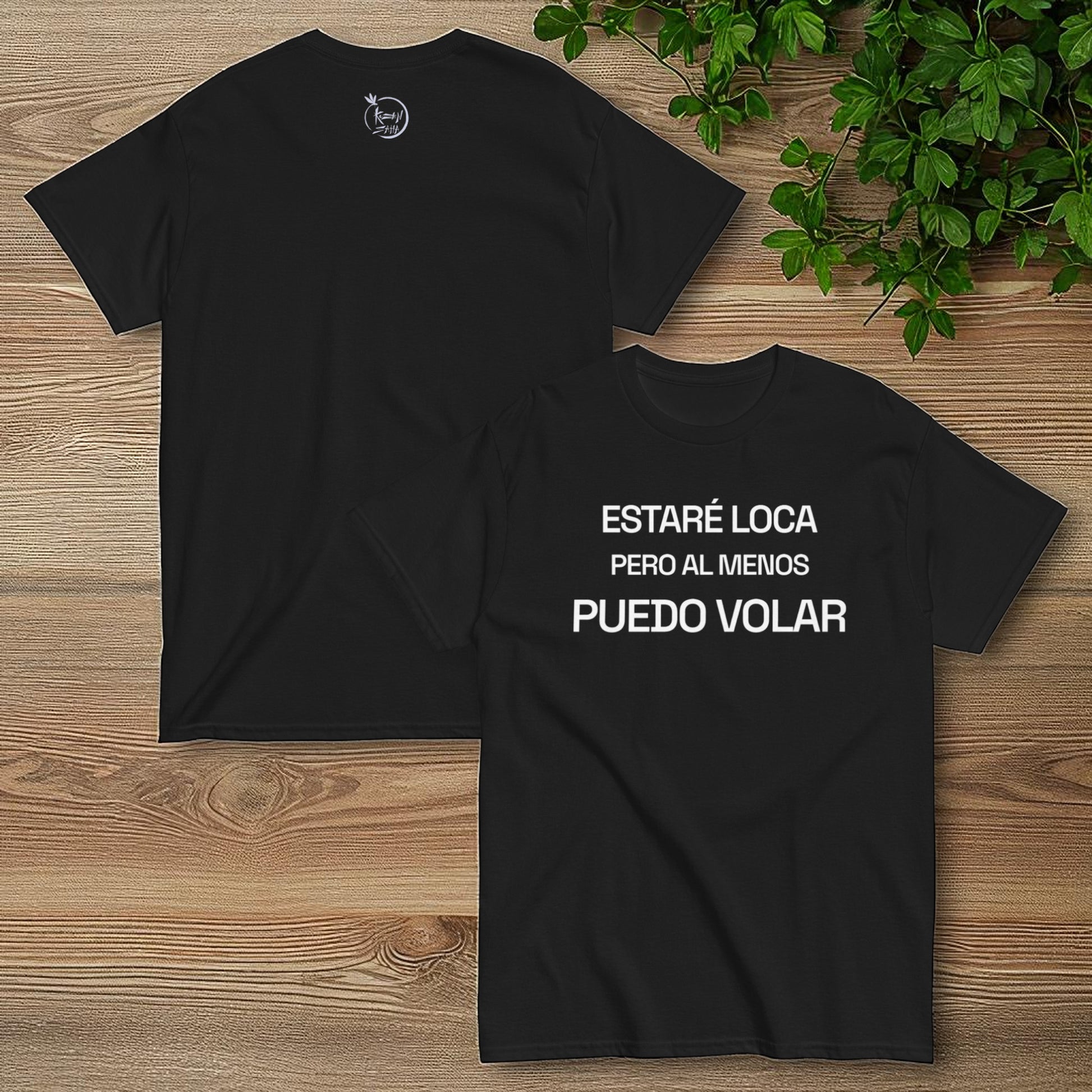 Camiseta negra frente y espalda con la frase estare loca pero al menos puedo volar sobre fondo de madera