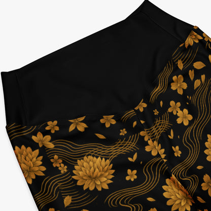 Detalle de cintura y flores doradas sobre fondo negro en los leggings Crisantemo.