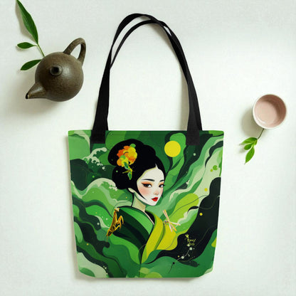 Bolso tote Geisha Esperanza sobre superficie blanca, composición lifestyle con hojas verdes y pequeñas piezas de cerámica.