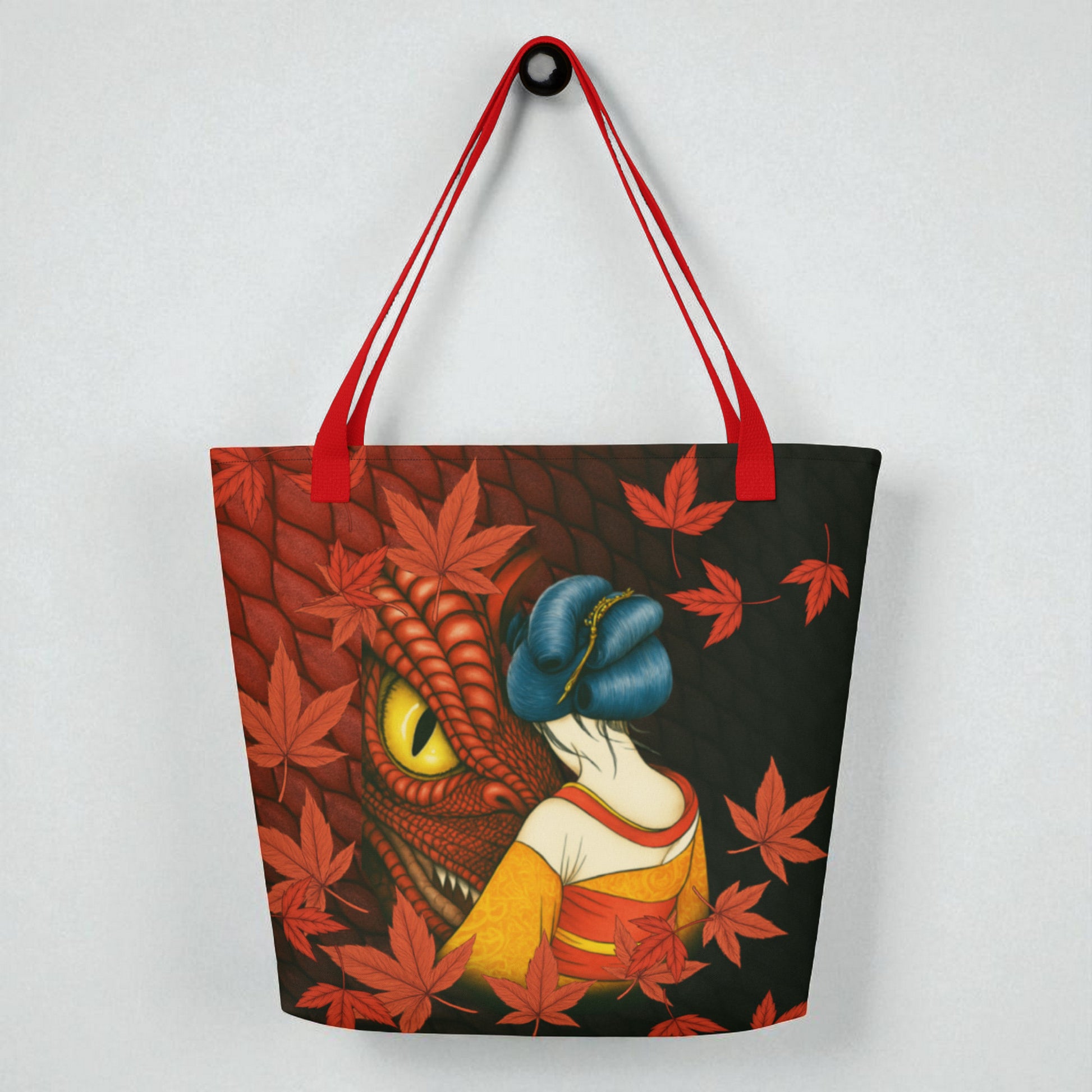 Bolso tote La mirada del Dragón, vista frontal con asas rojas sobre superficie blanca, diseño con ojo de dragón y hojas.