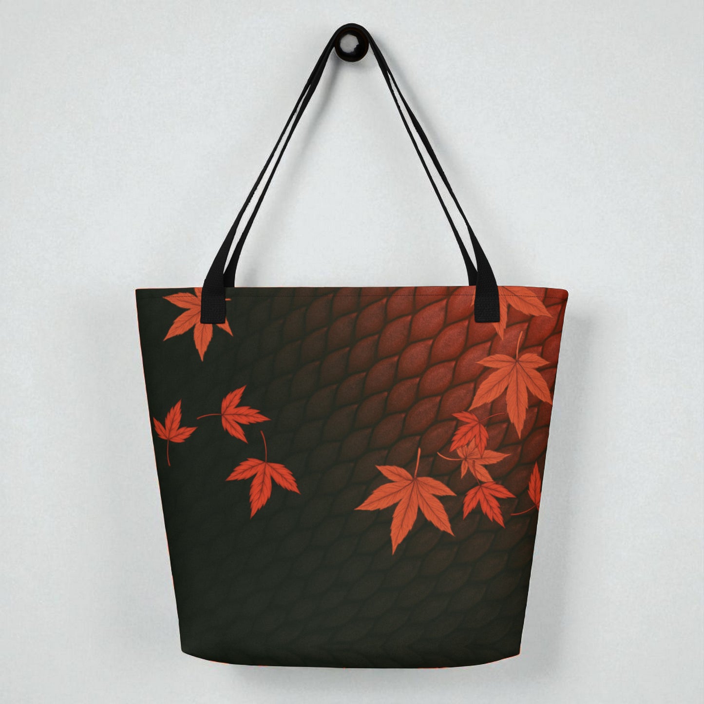 Bolso tote La mirada del Dragón colgado sobre pared clara, vista posterior con estampado de hojas de arce rojas.
