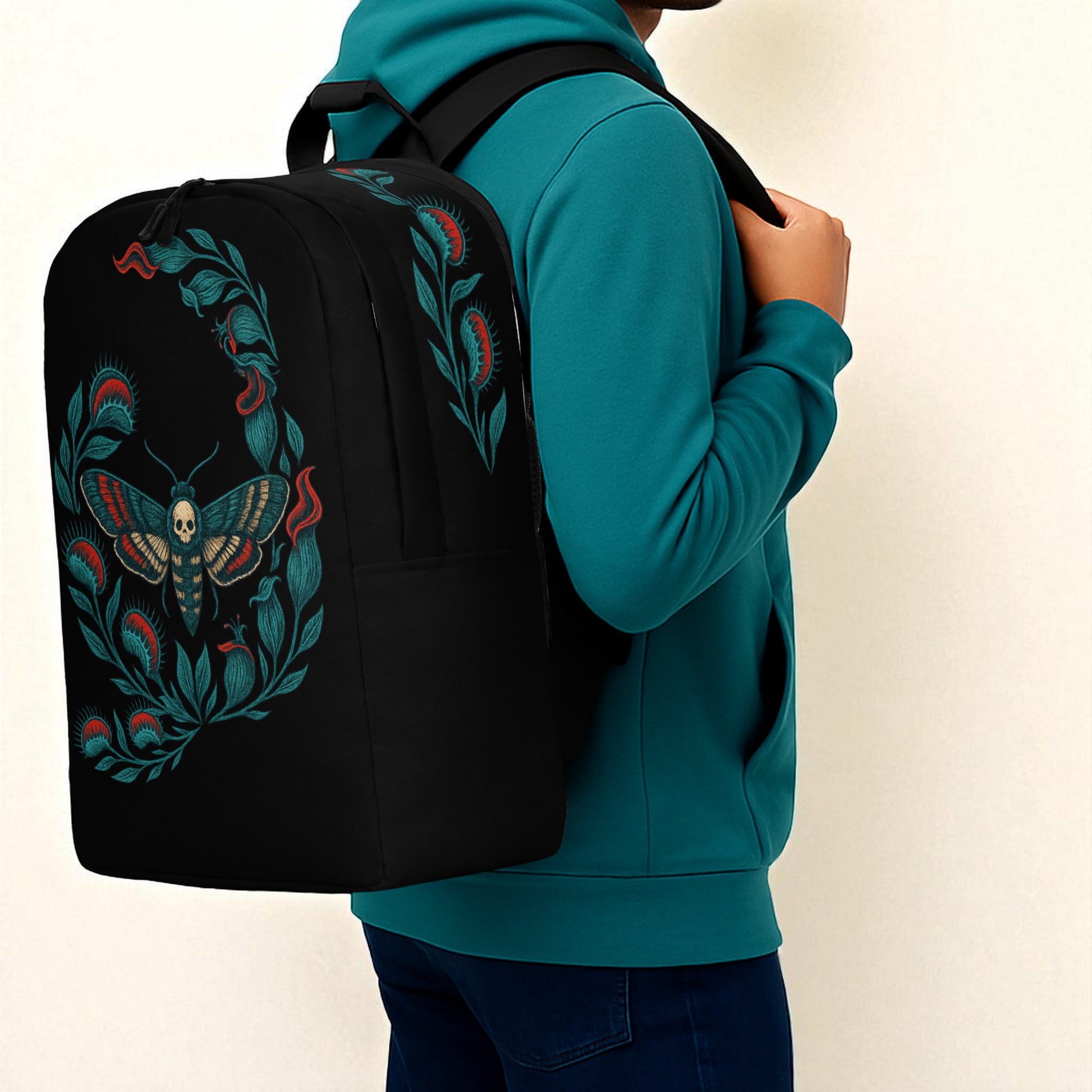 Plano medio del hombro con sudadera azul petróleo y mochila negra con polilla calavera en vista lateral.