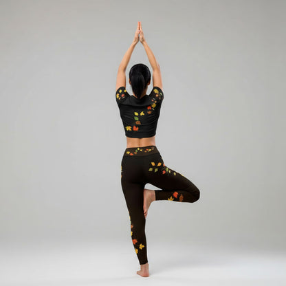 Postura de árbol yoga espalda  mostrando leggings negros con hojas otoñales