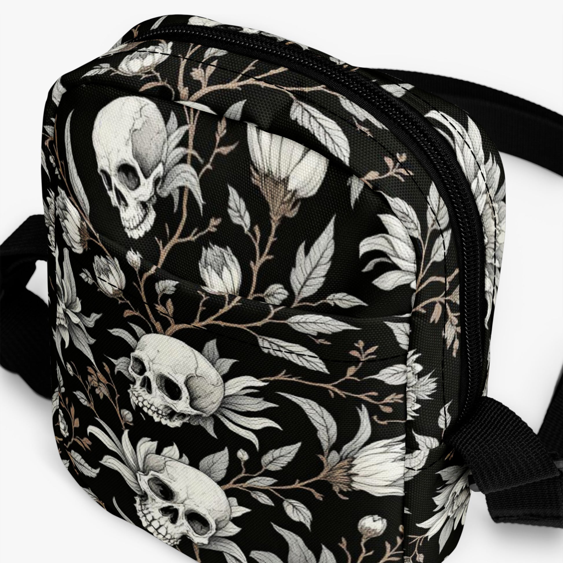 Bolso bandolera negro con calaveras y flores vista frontal del producto