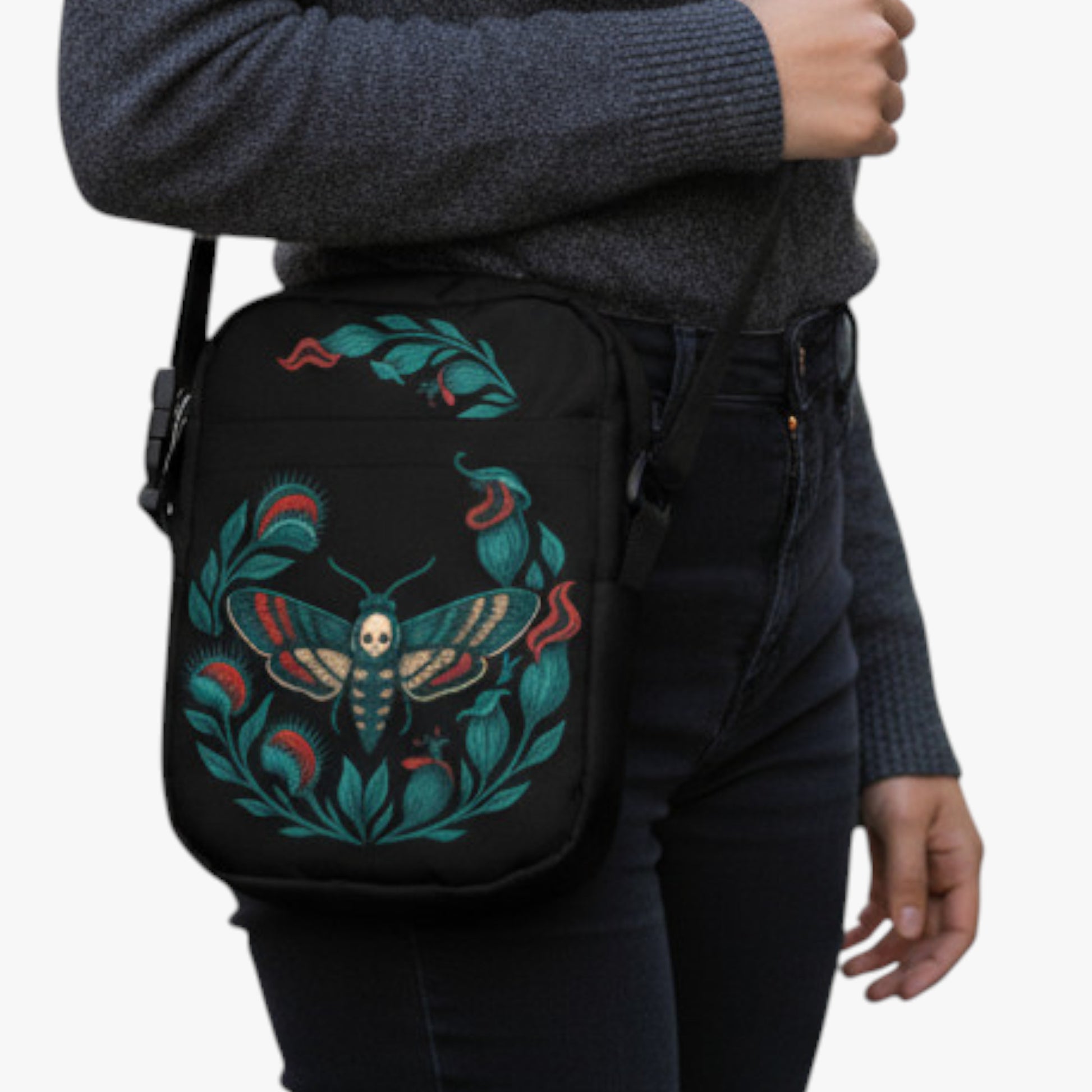 Primer plano de bolso urbano negro con estampado de polilla azul y verde, colgado al costado.