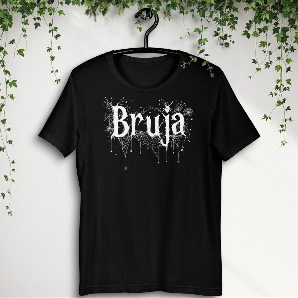 Camiseta negra unisex Bruja. Vista frontal en percha con diseño gótico blanco.