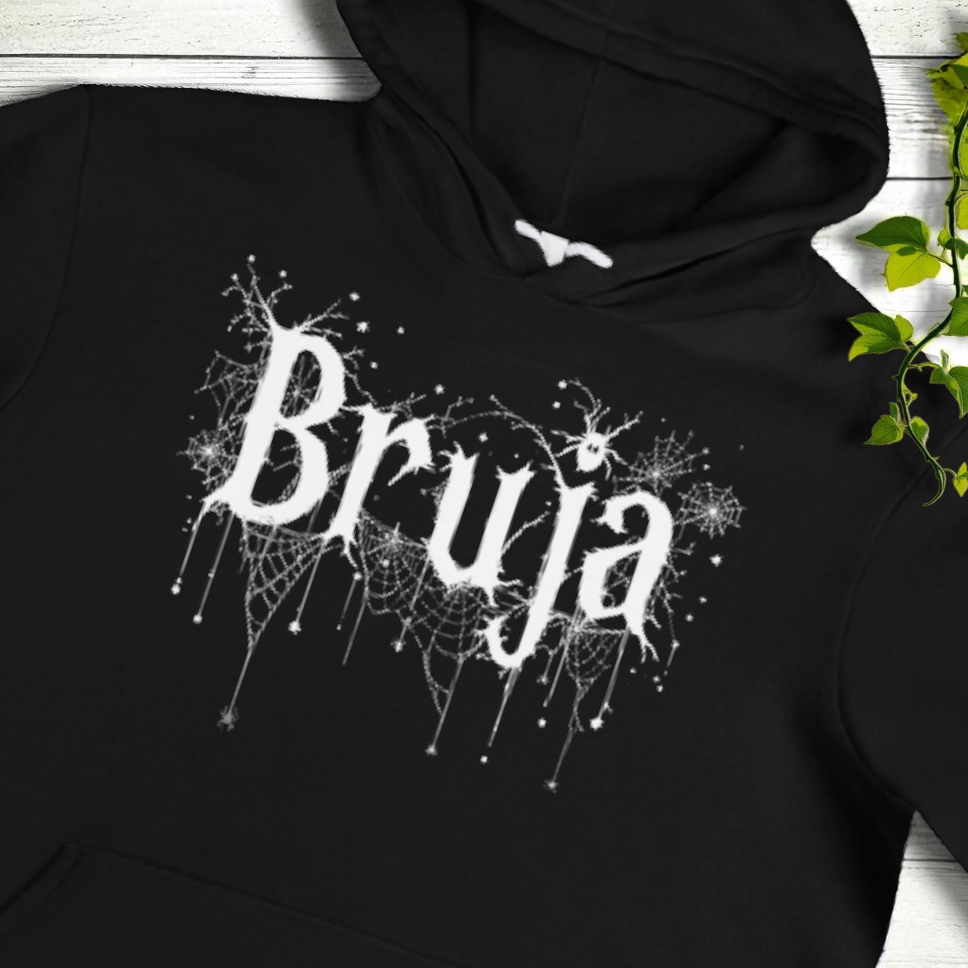 Primer plano del estampado Bruja en blanco con telarañas sobre sudadera negra
