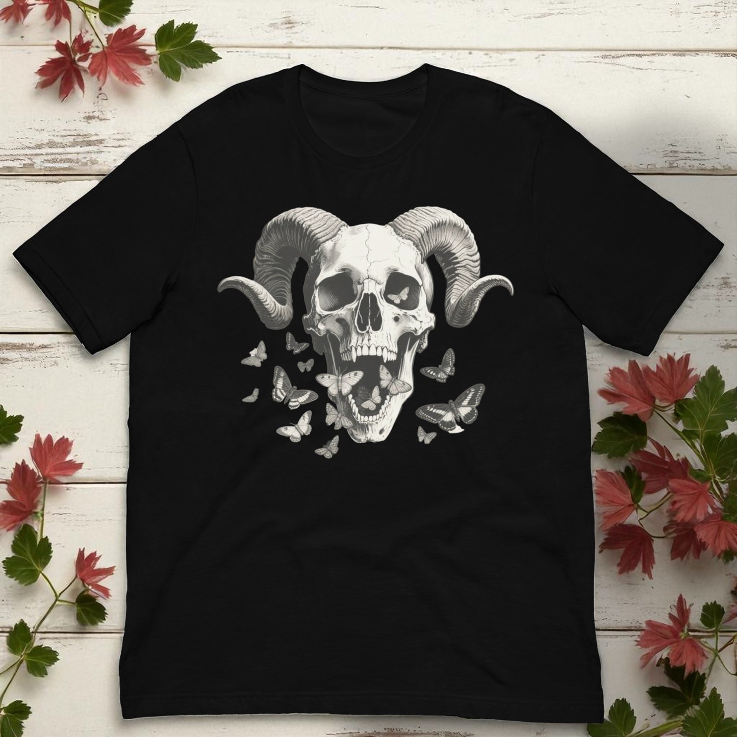 Camiseta negra unisex con calavera con cuernos y mariposas foto en flat lay con hojas decorativas