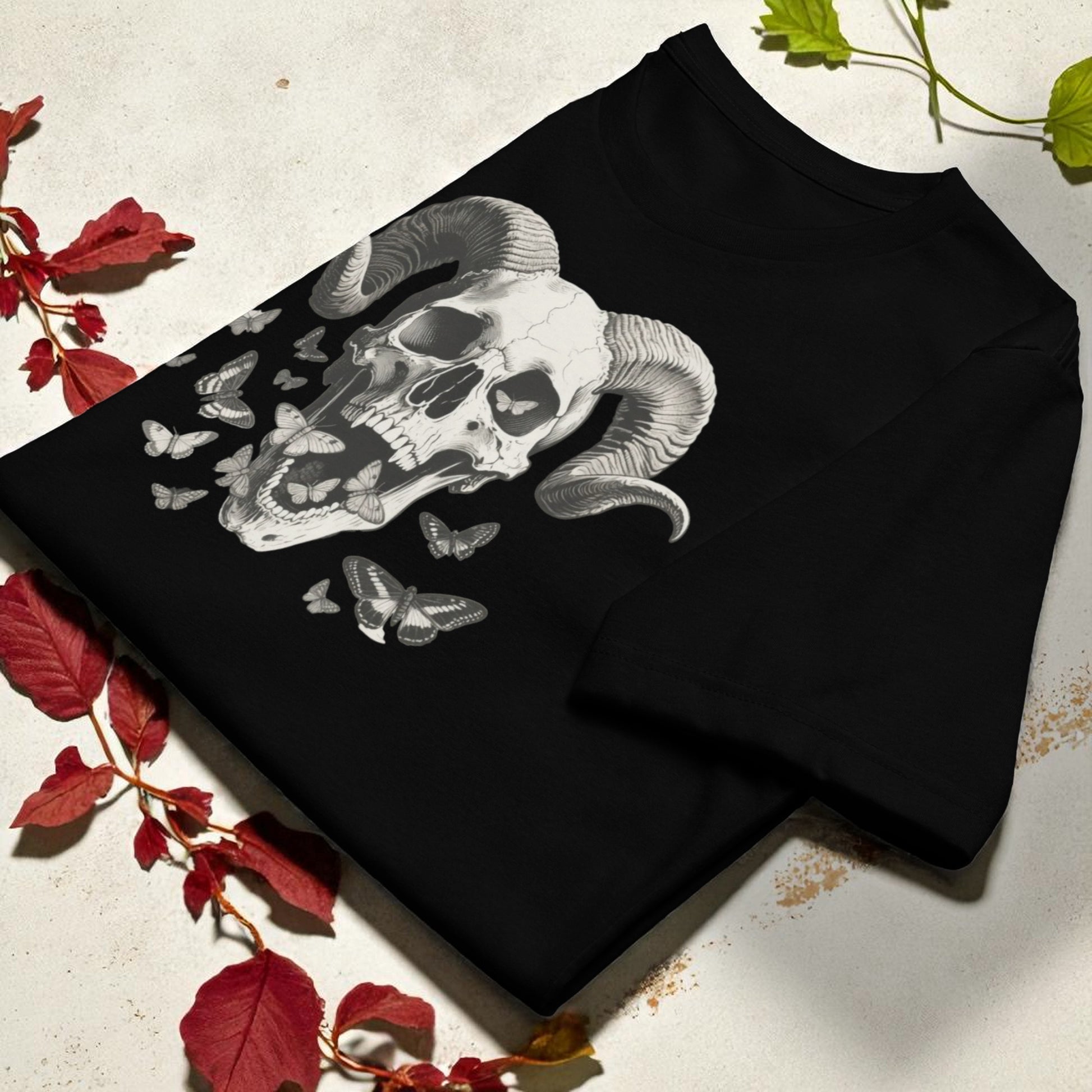 Camiseta negra con calavera con cuernos y mariposas apilada en ángulo diagonal para mostrar el diseño