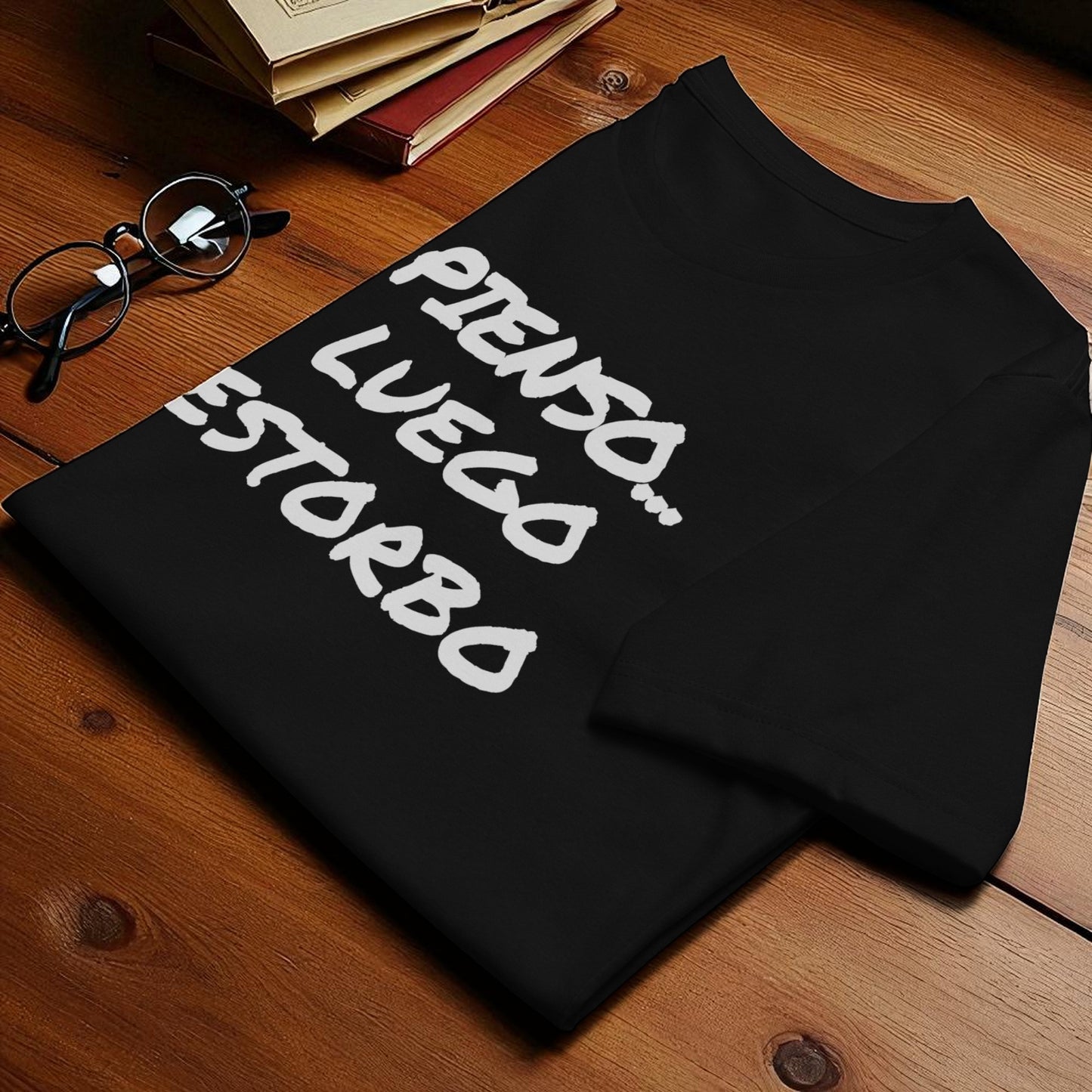 Camiseta negra doblada con la frase, vista de detalle sobre mesa.