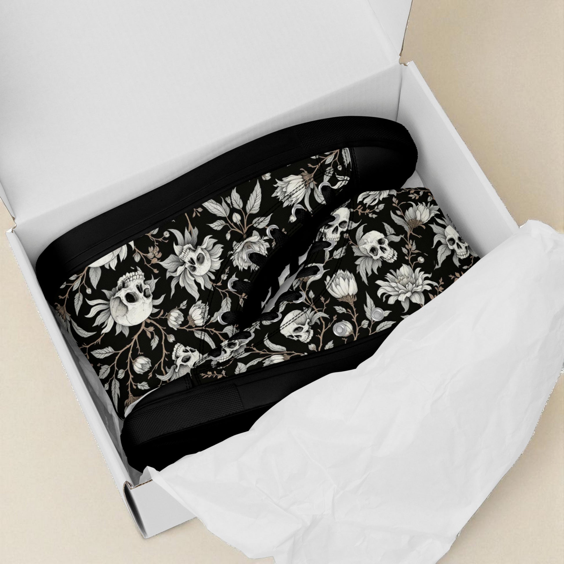 Zapatillas altas negras con calaveras y flores en caja abierta con papel