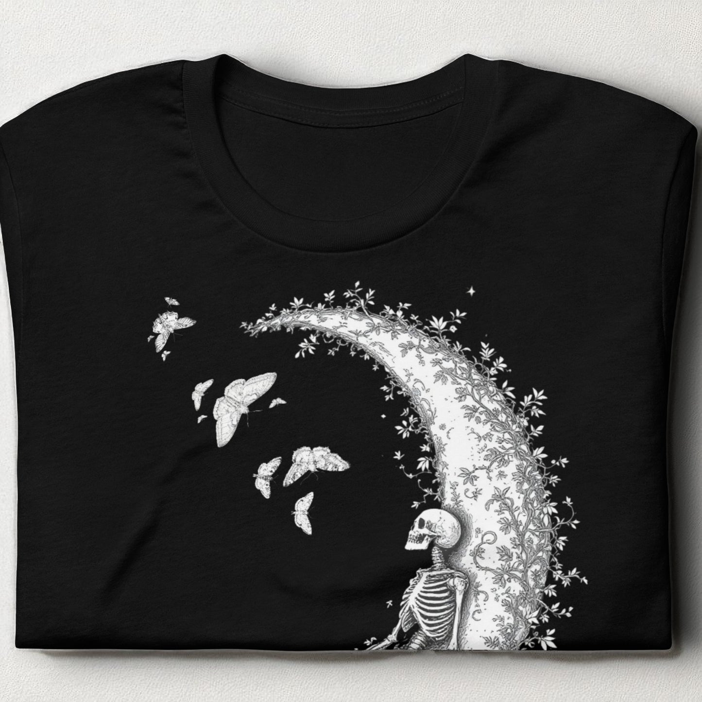 Camiseta negra con esqueleto sobre la luna doblada sobre mesa