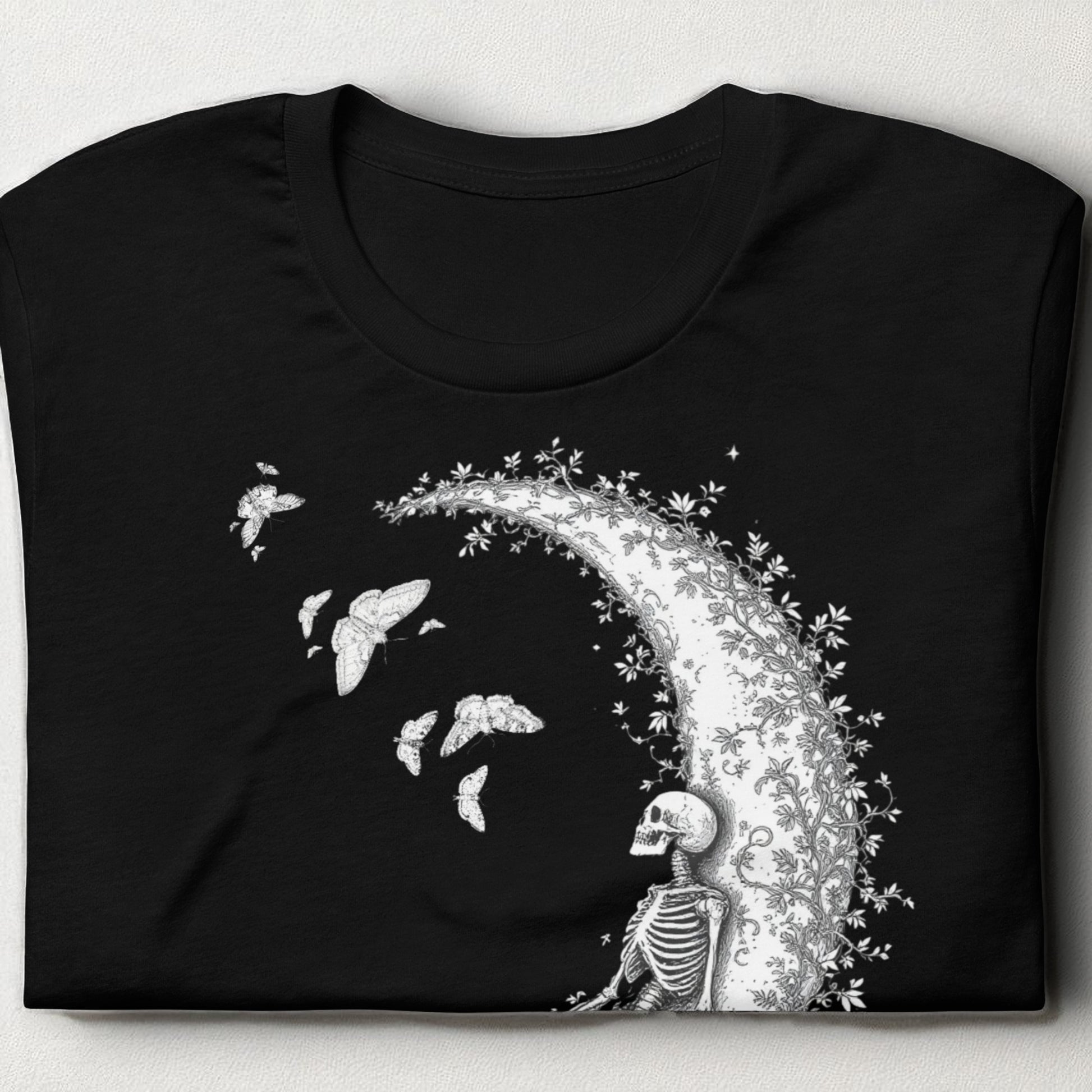 Camiseta negra con esqueleto sobre la luna doblada sobre mesa