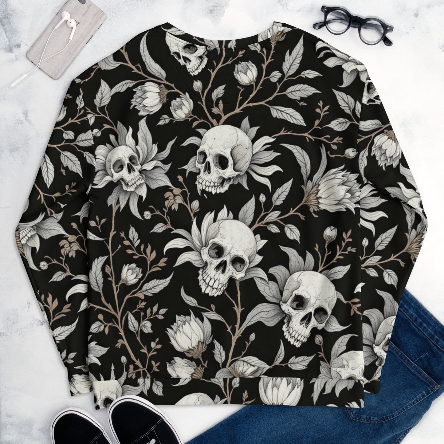 Sudadera unisex negra con flores y calaveras colocada sobre superficie vista completa