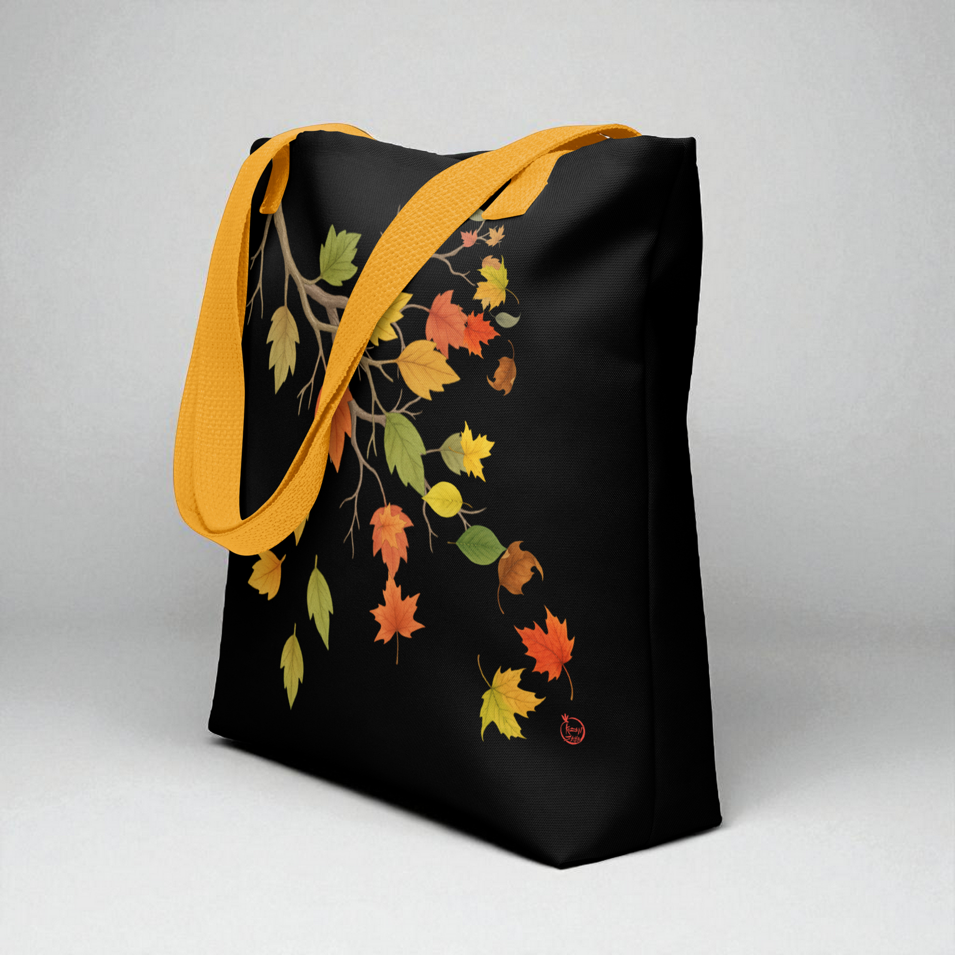 Bolsa tote negra con hojas de otoño y asas amarillas, vista lateral del ancho