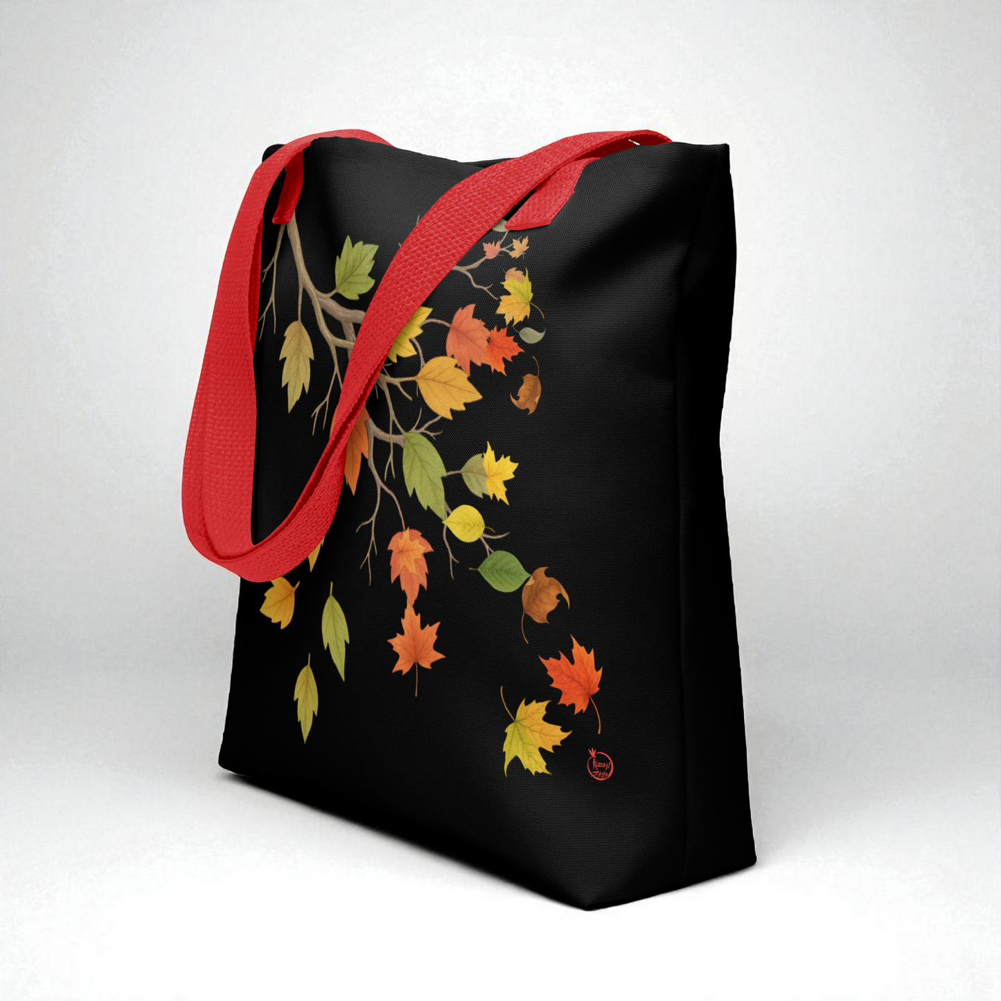 Bolsa tote negra con hojas de otoño, asas rojas, vista 3/4 para profundidad